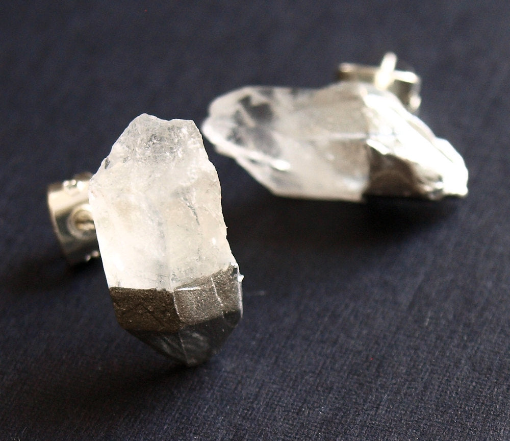 A pair of Silver & Raw Quartz Chunk Earrings with metal bases sit gracefully on a dark surface, embodying spiritual growth. Expertly gift wrapped, they make an ideal present for any occasion.