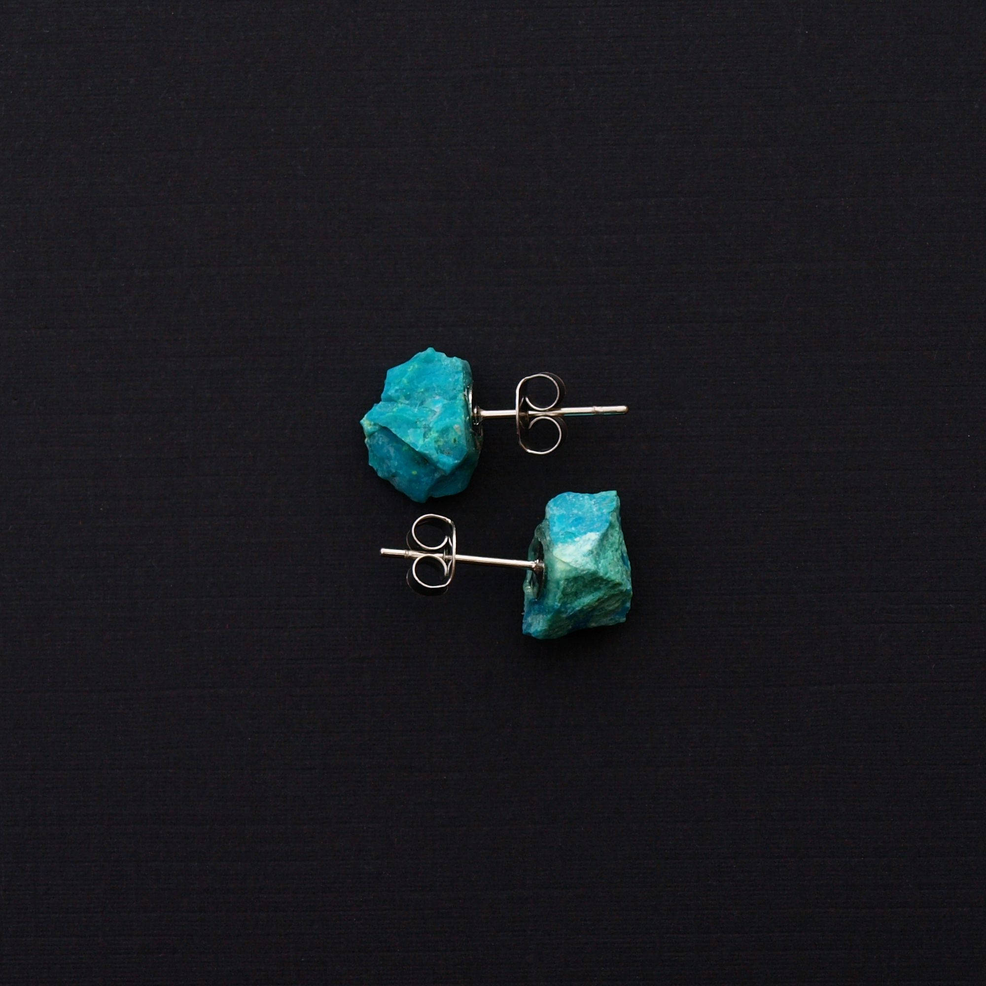 Close-up of Raw Chrysocolla Chunk Earrings, Rock Stud Earrings, Crystal Earrings with surgical steel earring posts on a dark gray background.