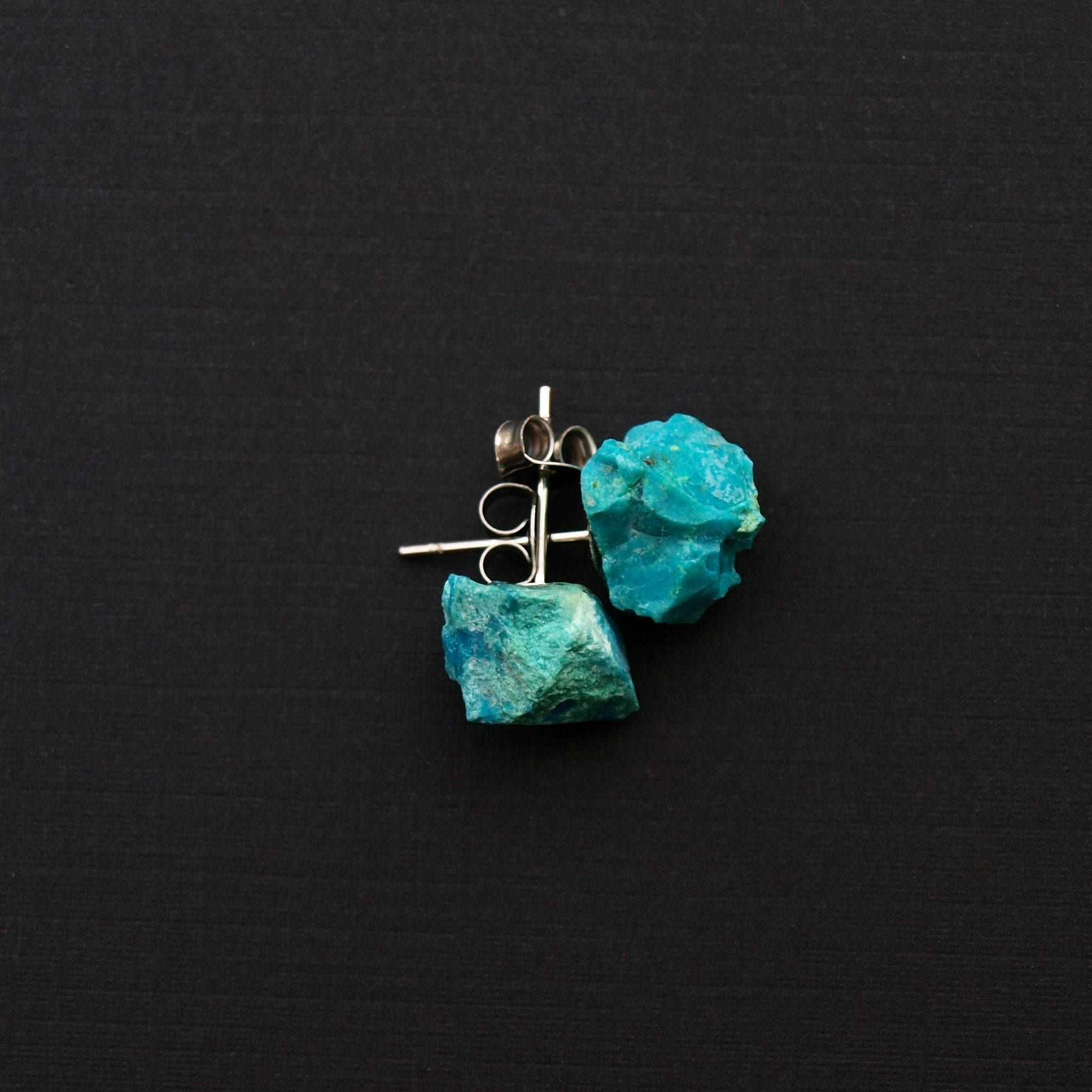 Close-up of Raw Chrysocolla Chunk Earrings, Rock Stud Earrings, Crystal Earrings with surgical steel earring posts on a dark gray background.