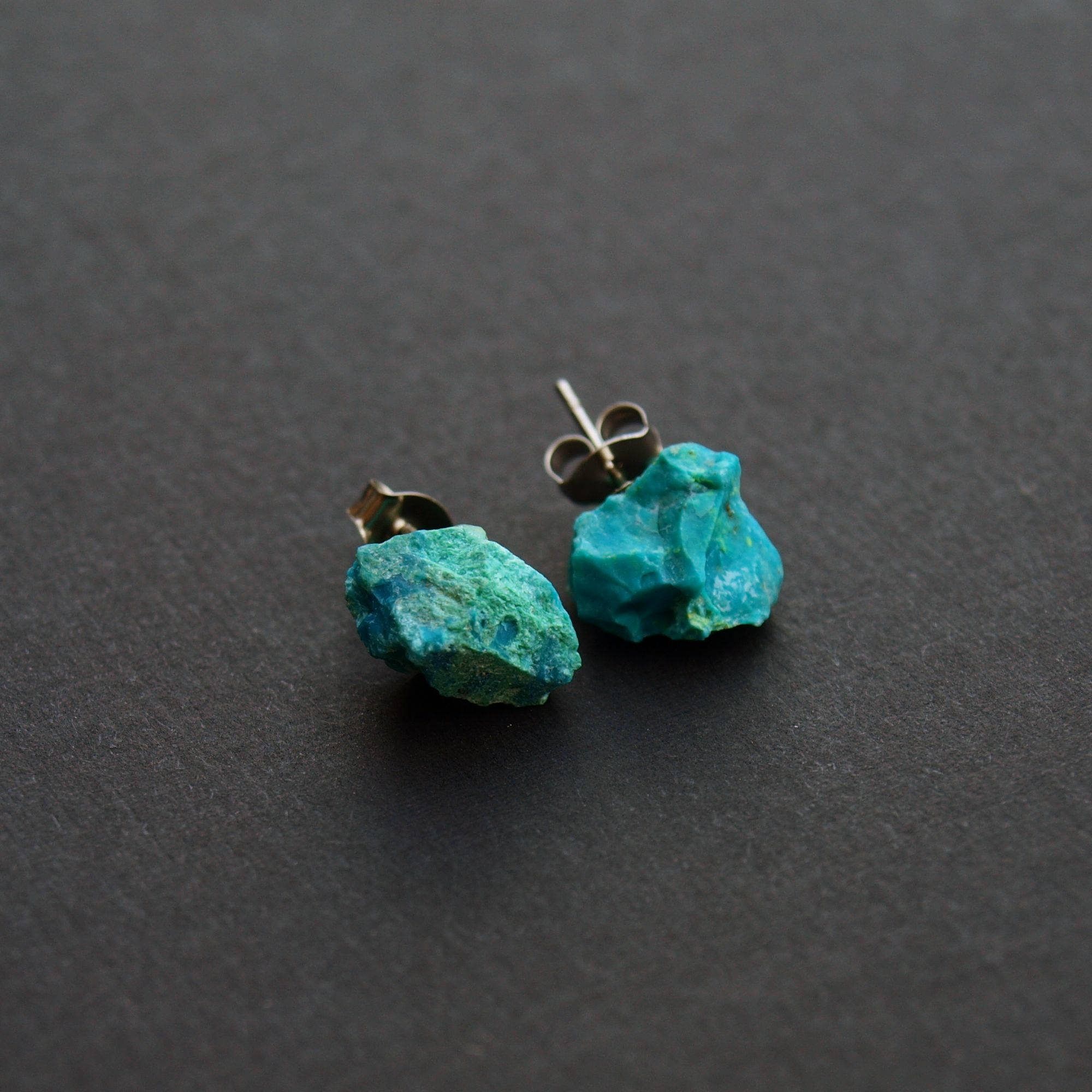 Close-up of Raw Chrysocolla Chunk Earrings, Rock Stud Earrings, Crystal Earrings with surgical steel earring posts on a dark gray background.