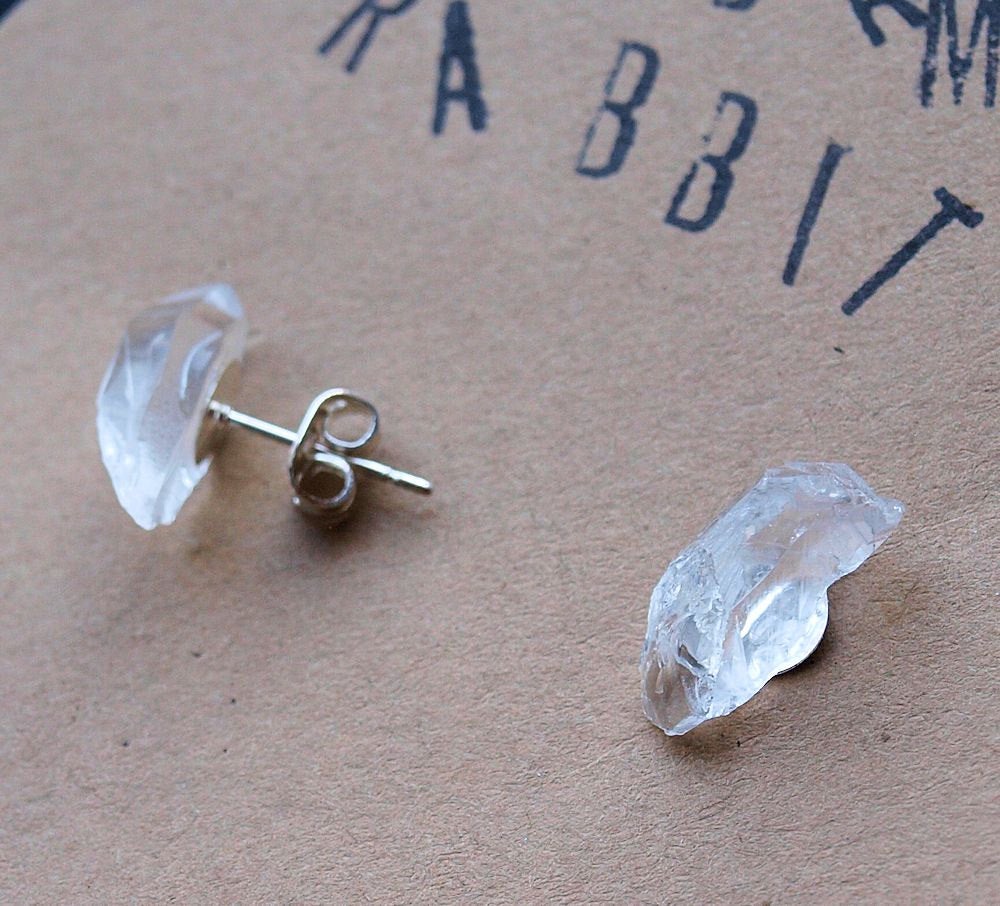 Close-up of a striking pair from the Raw Quartz Chunk Earrings collection, showcasing rough, clear quartz stones set in silver on a dark surface, they make a statement in any collection.