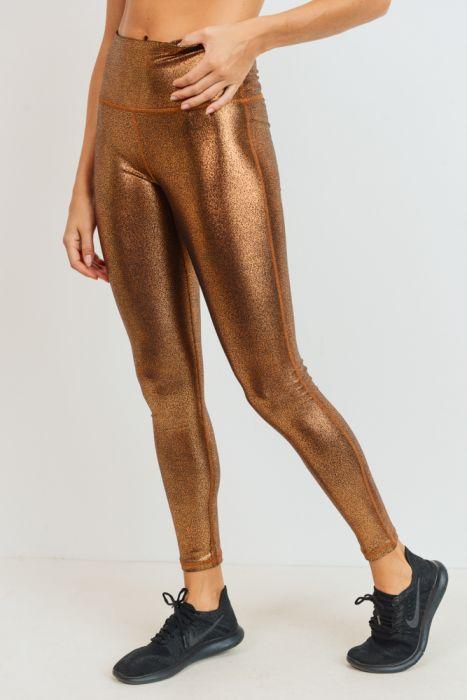 Person wearing Highwaist Foil Scale Print Full Leggings - Gold and black athletic shoes stands against a neutral background. The model's midsection and legs, highlighted by the tummy control feature of the leggings, are visible.