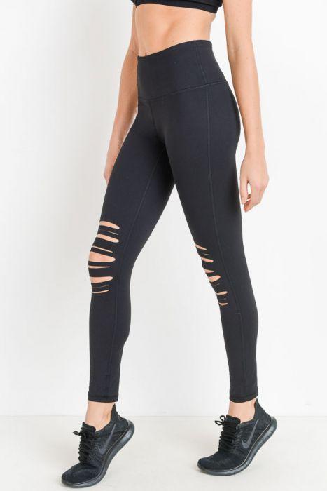 A person is wearing a black crop top and High Waist Laser Cut Ripped Knee Leggings boasting moisture-wicking properties, paired with black shoes.