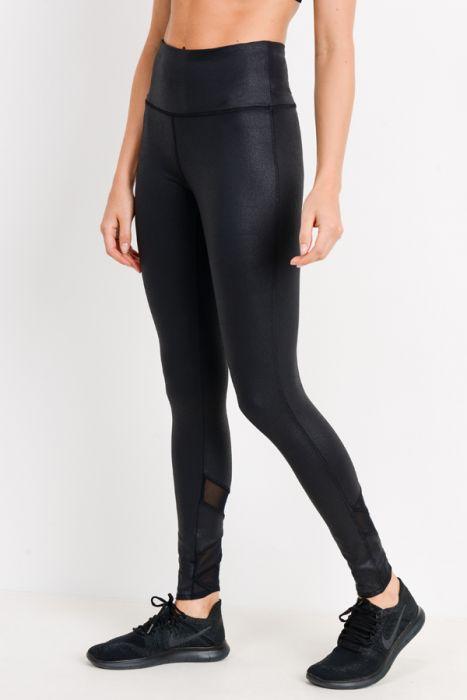 A person wearing Highwaist Foil Zig-Zag Mesh Leggings in a shiny black foil fabric and black shoes stands against a plain background.