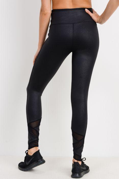 A person wearing Highwaist Foil Zig-Zag Mesh Leggings in a shiny black foil fabric and black shoes stands against a plain background.
