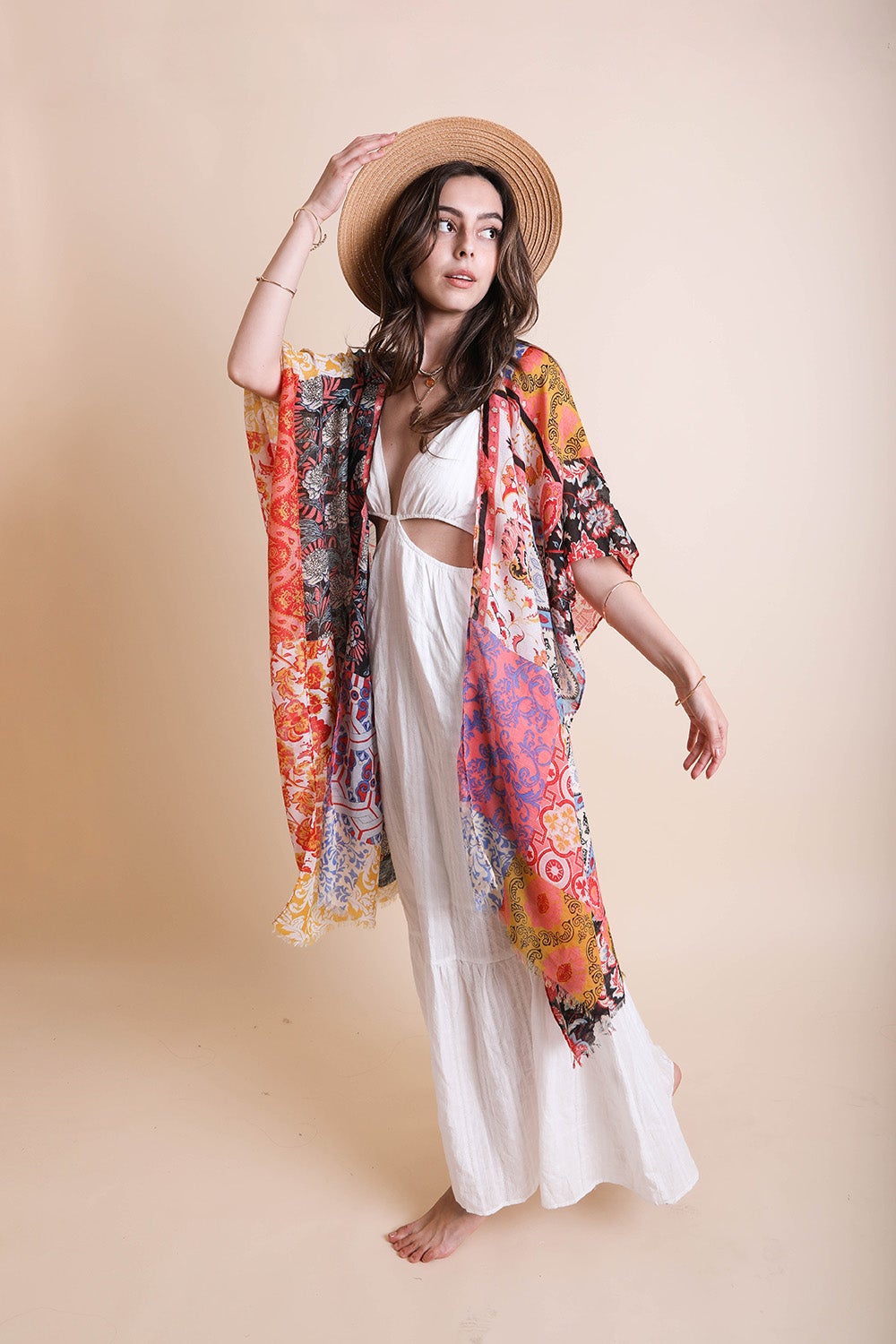 A person in a Boho Patchwork Kimono over their everyday outfit and a hat stands in an outdoor area with a wooden sink and mirror.