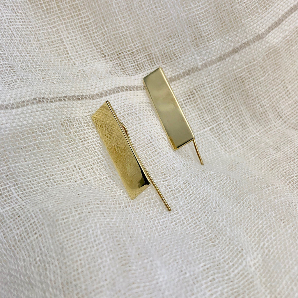 The Bombshell Bar Earrings, made from recycled brass bombshells and featuring thin hooks, are elegantly displayed on a white background, highlighting the exquisite craftsmanship of artisan jewelry.