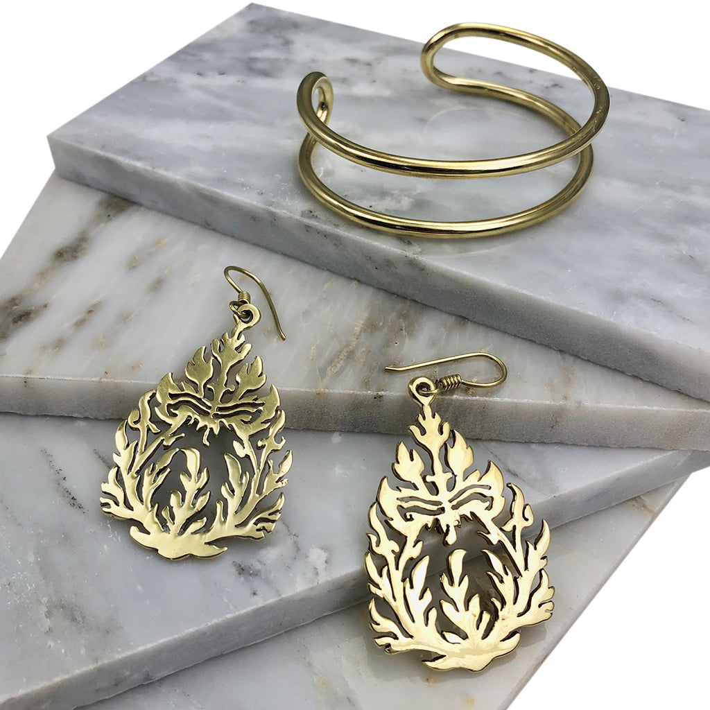 The Bombshell Wire Cuff is a gold double band cuff bracelet with an open-ended design, meticulously handmade in Cambodia. Crafted from recycled brass jewelry materials, this adjustable cuff combines both style and sustainability.