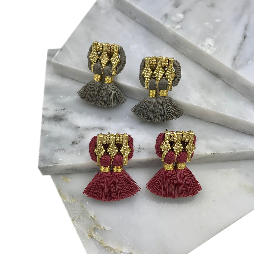 A pair of Jhumka Earrings in gold and black, showcasing detailed geometric designs with fringed ends.