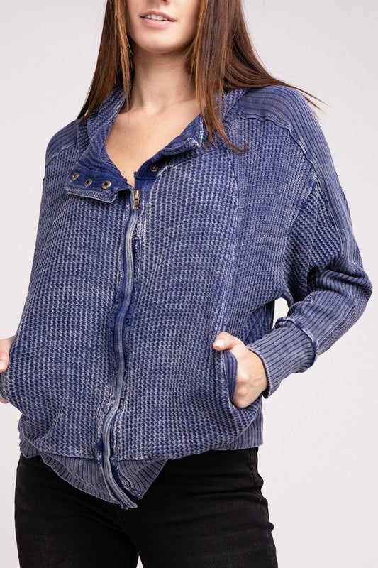 Woman in a Acid Wash Cotton Waffle Hooded Zip-Up Jacket with pockets and black pants, smiling and posing with hands on hips, against a light gray background.