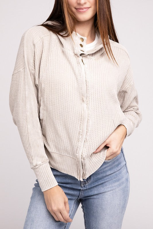 Woman in a Acid Wash Cotton Waffle Hooded Zip-Up Jacket with pockets and black pants, smiling and posing with hands on hips, against a light gray background.