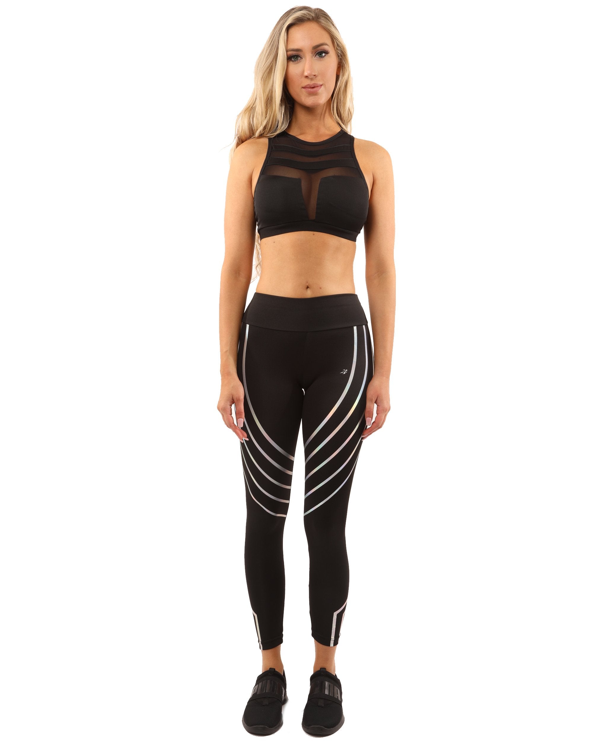 A person wears the sleek Laguna Set in black, featuring a sports bra with a mesh design and compression fit leggings, against a plain white background.