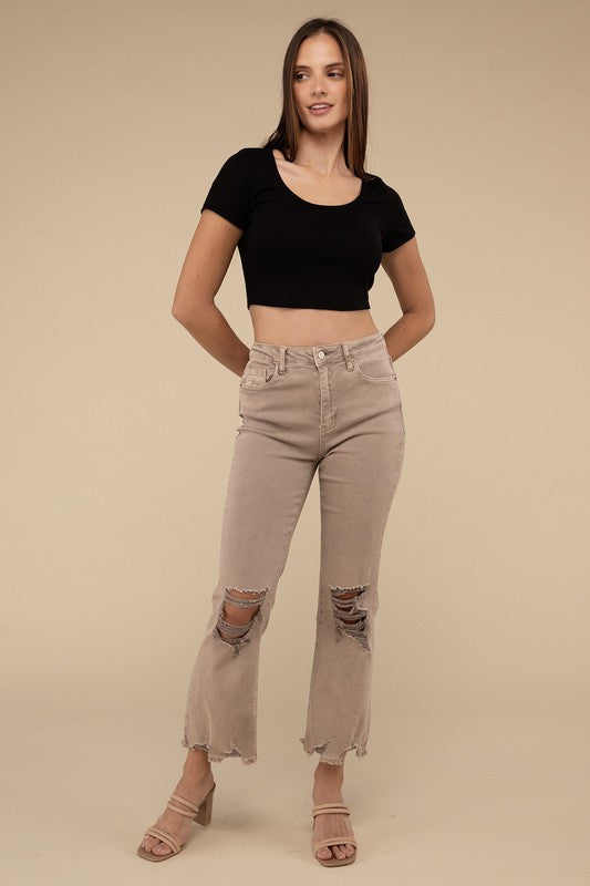 Person wearing acid washed high waist distressed straight pants and beige sandals against a neutral background.