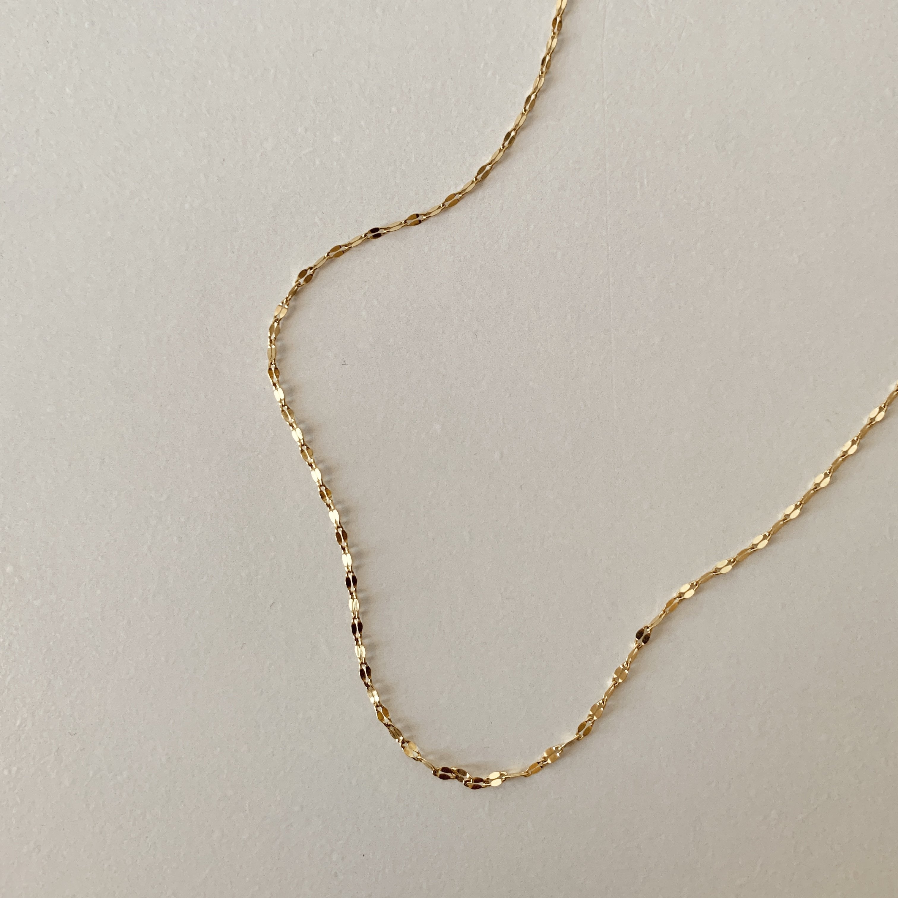 The Diana Choker Necklace, with its 18K gold plating, is elegantly displayed on a light gray backdrop, exuding subtle sophistication.