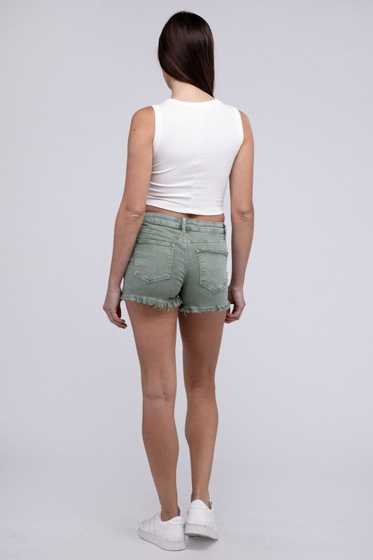 Close-up of a person wearing Acid Washed Frayed Cutoff Hem Shorts and a black top with lace-up details on the side.