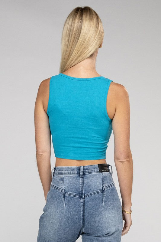 A woman with blonde hair smiling, wearing a Cotton Square Neck Cropped Cami Top and white pants, standing against a grey background.