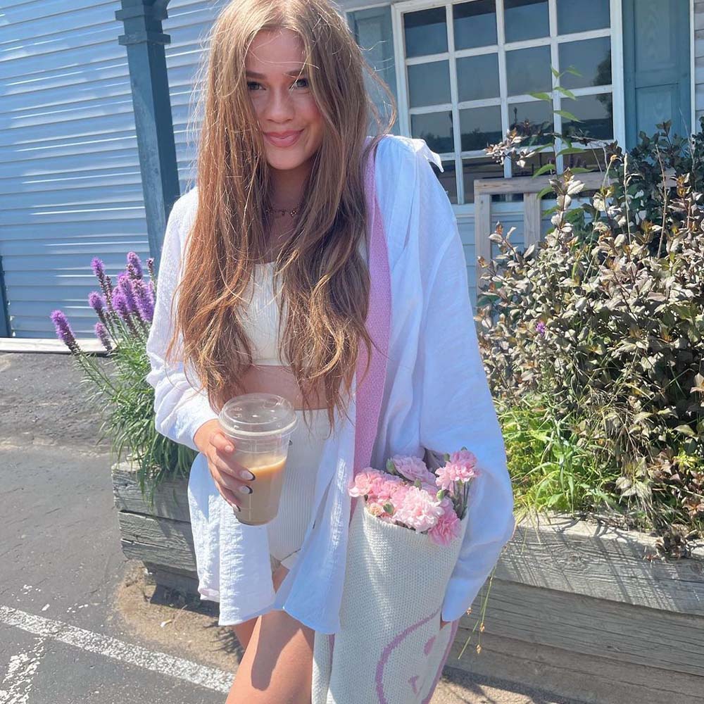 The Poppy Knit Bag boasts a retro-inspired smiley face design in vibrant orange and white, complete with patterned straps for a stylish touch.