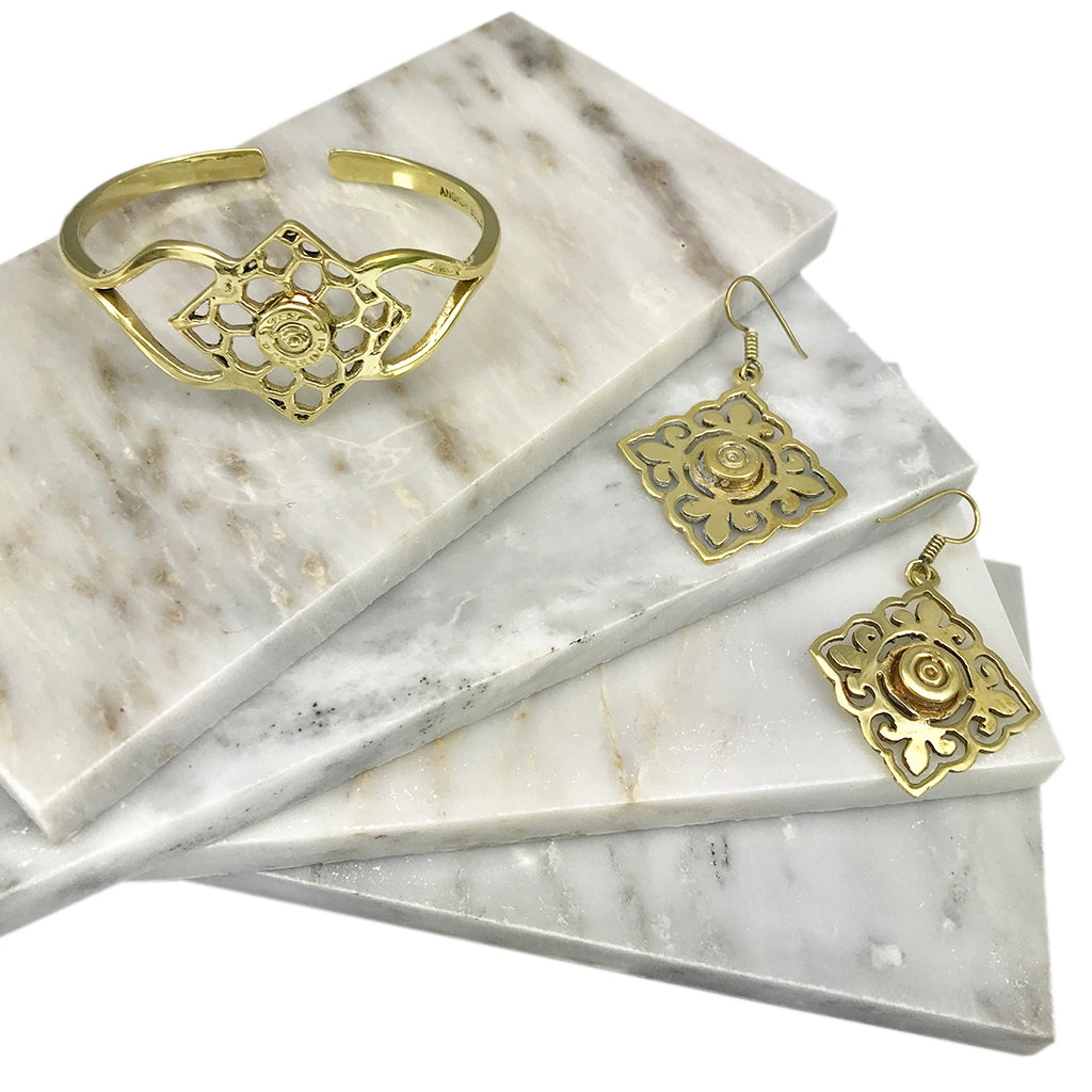 The Angkor Bullet Cuff is a stunning gold cuff bracelet that showcases an intricate openwork floral design, handcrafted with artisan craftsmanship. Made in Cambodia, this unique piece elegantly combines history and artistry by using recycled bombshell jewelry.