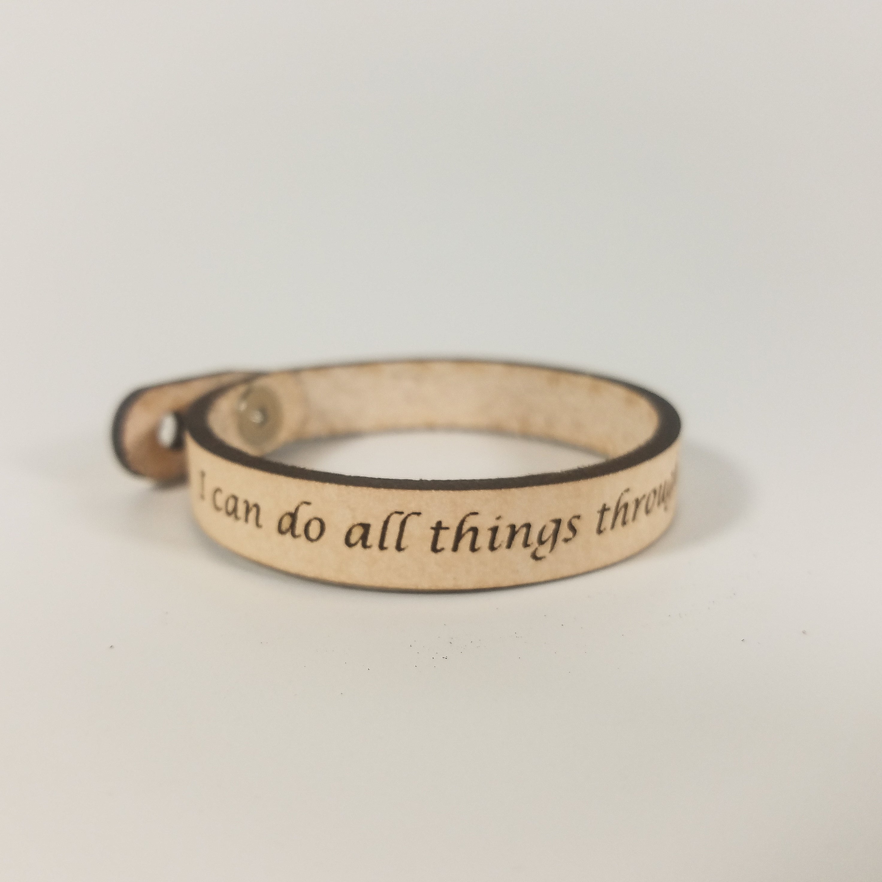 The Spiritual Quote Bracelet, made of genuine leather and featuring an adjustable button closure, skillfully blends style with motivation by showcasing the inspirational message: "I can do all things through him who strengthens me.