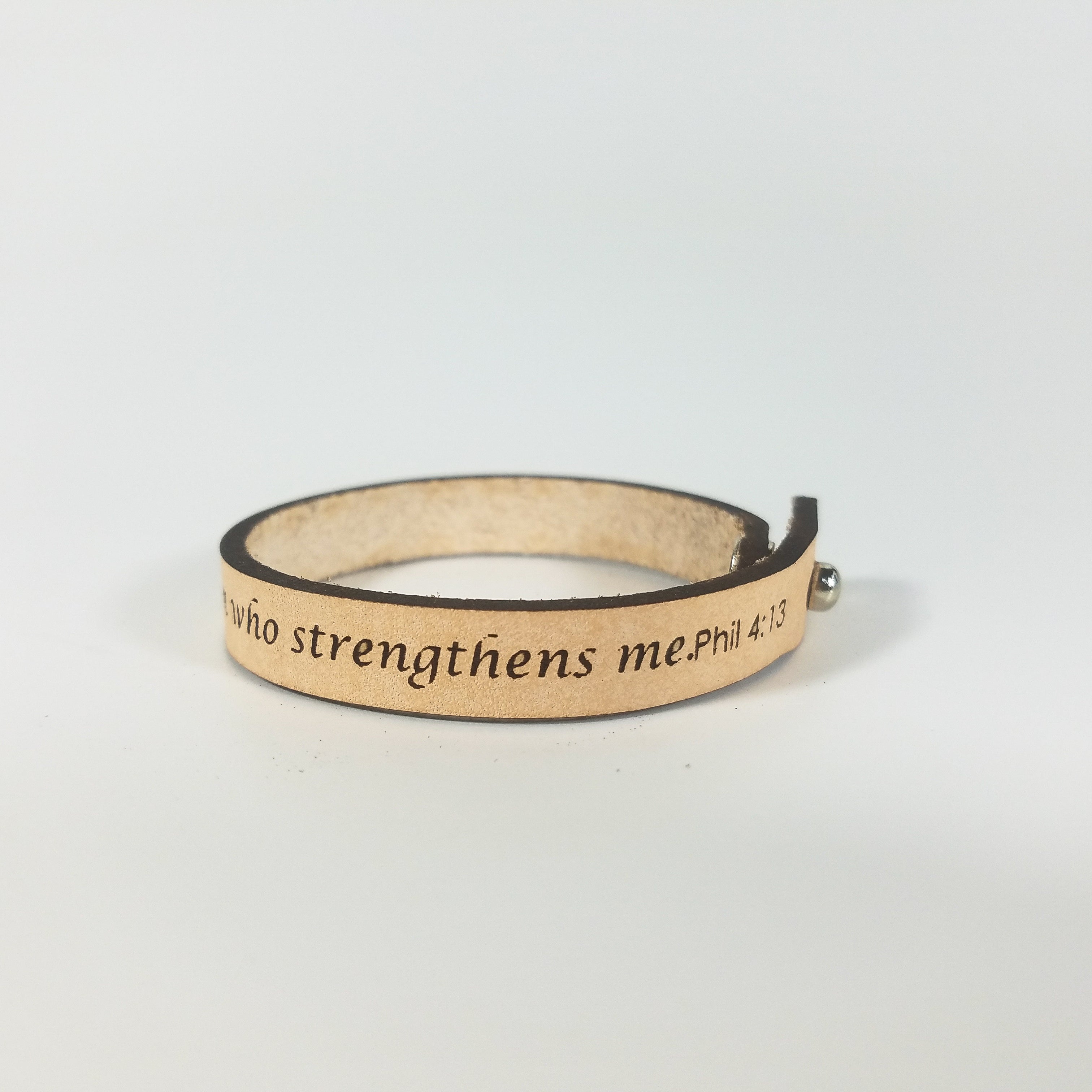 The Spiritual Quote Bracelet, made of genuine leather and featuring an adjustable button closure, skillfully blends style with motivation by showcasing the inspirational message: "I can do all things through him who strengthens me.