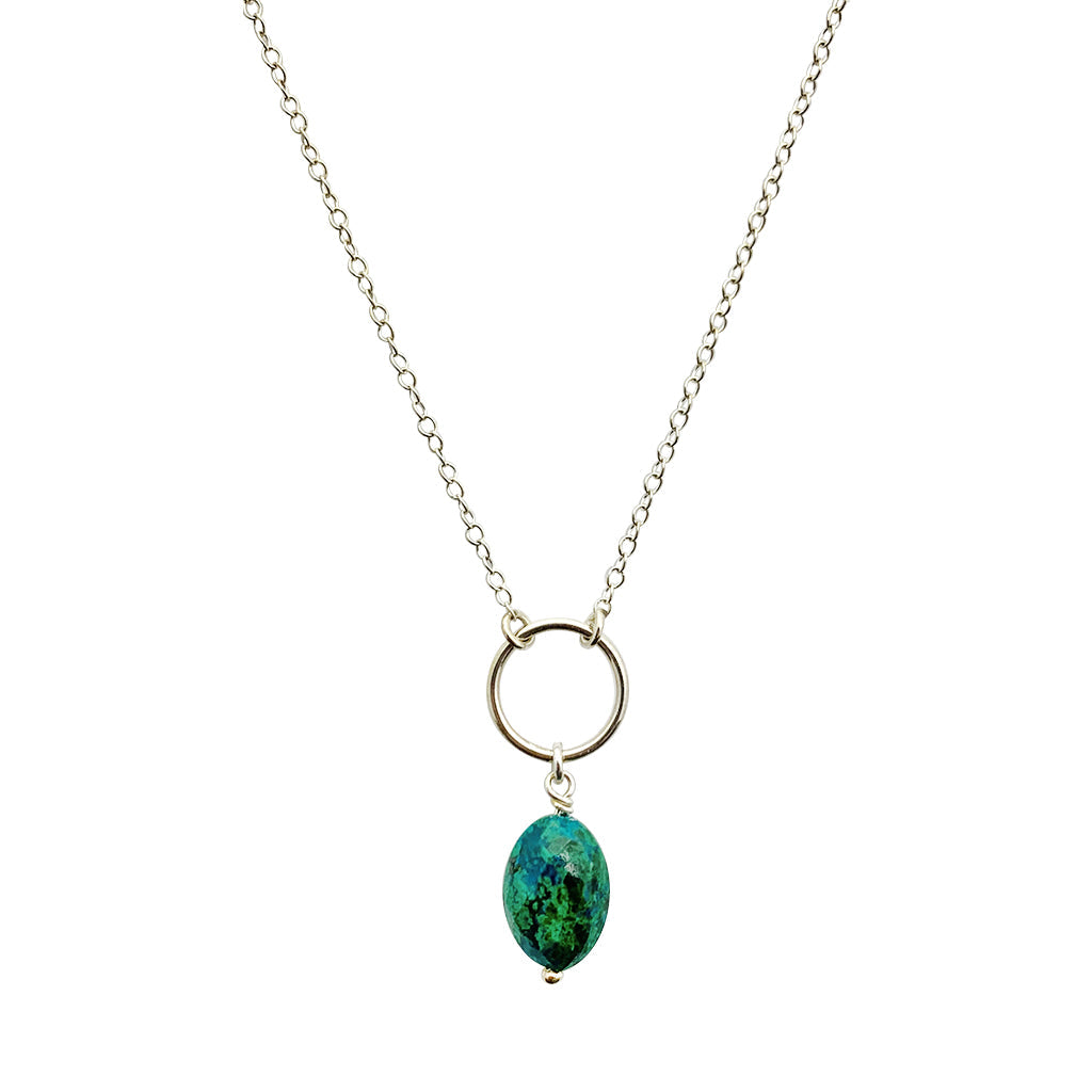 The Chrysocolla Circle Necklace is a handcrafted piece that includes a silver chain and a circular pendant, highlighting a dazzling Peruvian chrysocolla gemstone in rich green-blue tones.