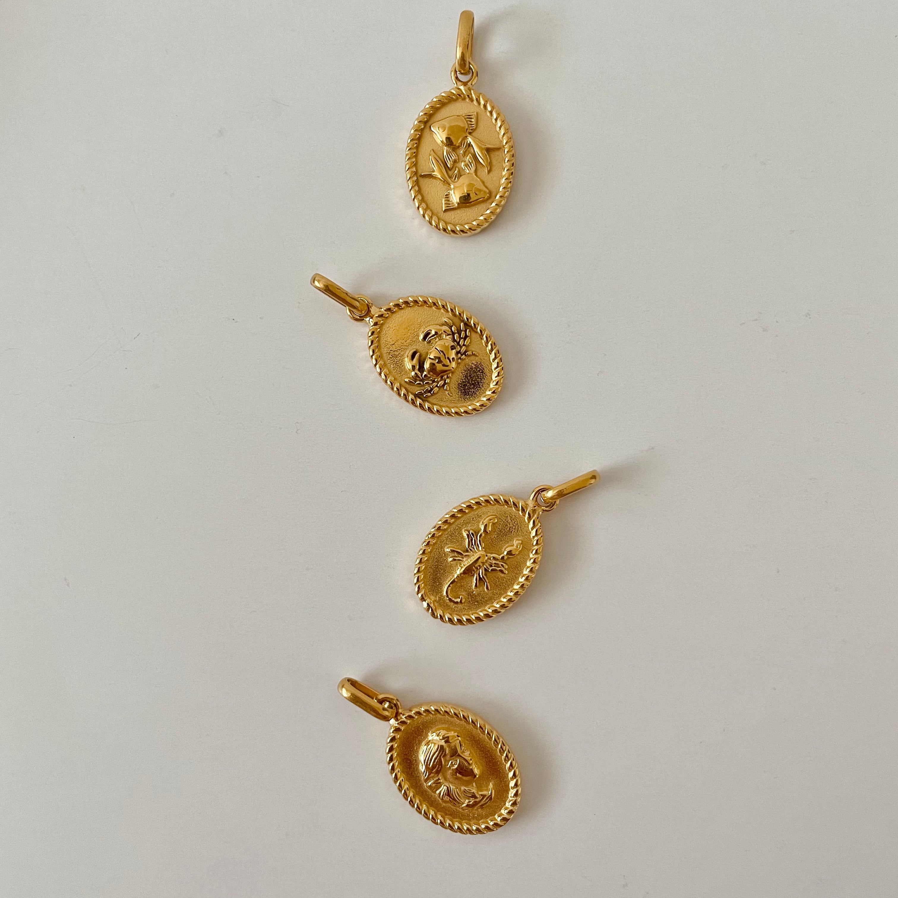 The Zodiac 2.0 Necklace - Gold features four gold-plated pendants with intricate designs, displayed vertically on a simple background, making it an ideal choice for an astrological necklace or hypoallergenic jewelry option.