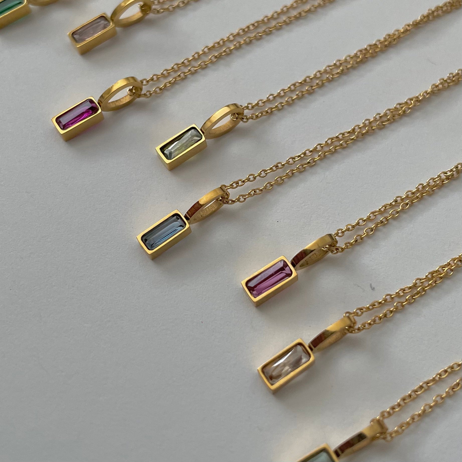 Birthstone necklaces, each featuring a rectangular gemstone pendant and thoughtfully handcrafted in Canada, are arranged neatly on a light surface.