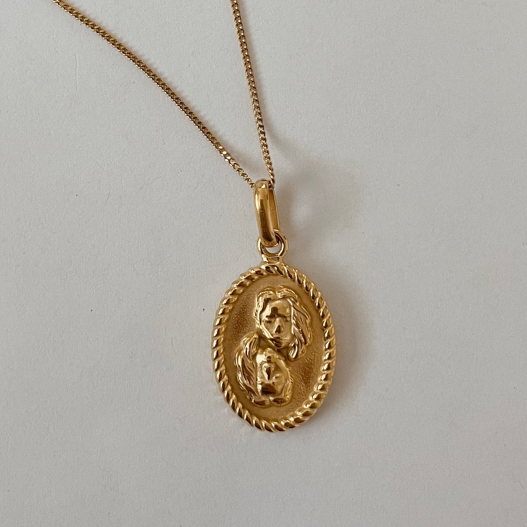 The Zodiac 2.0 Necklace - Gold features four gold-plated pendants with intricate designs, displayed vertically on a simple background, making it an ideal choice for an astrological necklace or hypoallergenic jewelry option.