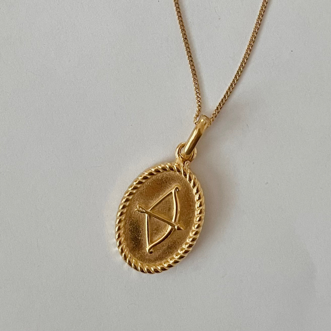 The Zodiac 2.0 Necklace - Gold features four gold-plated pendants with intricate designs, displayed vertically on a simple background, making it an ideal choice for an astrological necklace or hypoallergenic jewelry option.