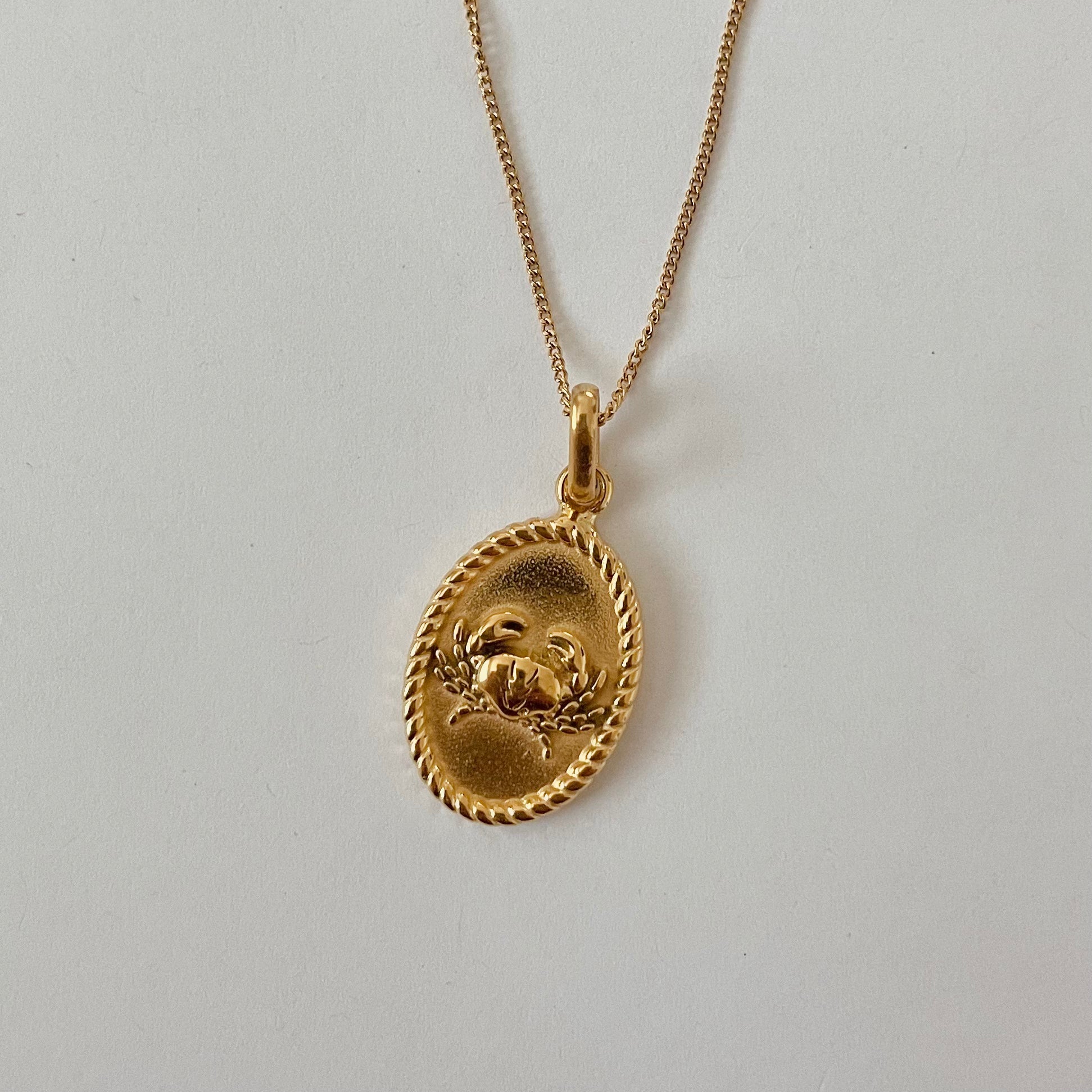 The Zodiac 2.0 Necklace - Gold features four gold-plated pendants with intricate designs, displayed vertically on a simple background, making it an ideal choice for an astrological necklace or hypoallergenic jewelry option.