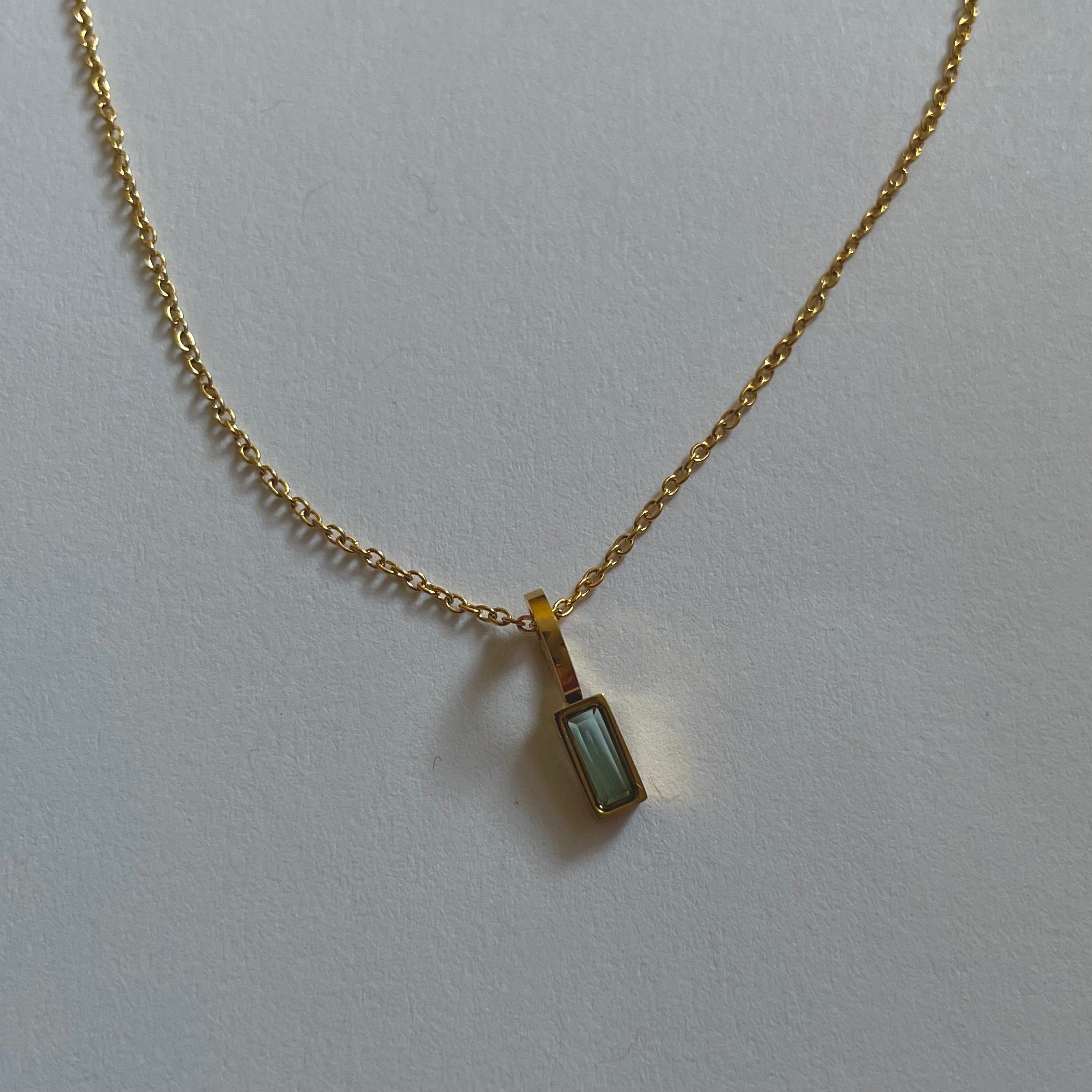 Birthstone necklaces, each featuring a rectangular gemstone pendant and thoughtfully handcrafted in Canada, are arranged neatly on a light surface.