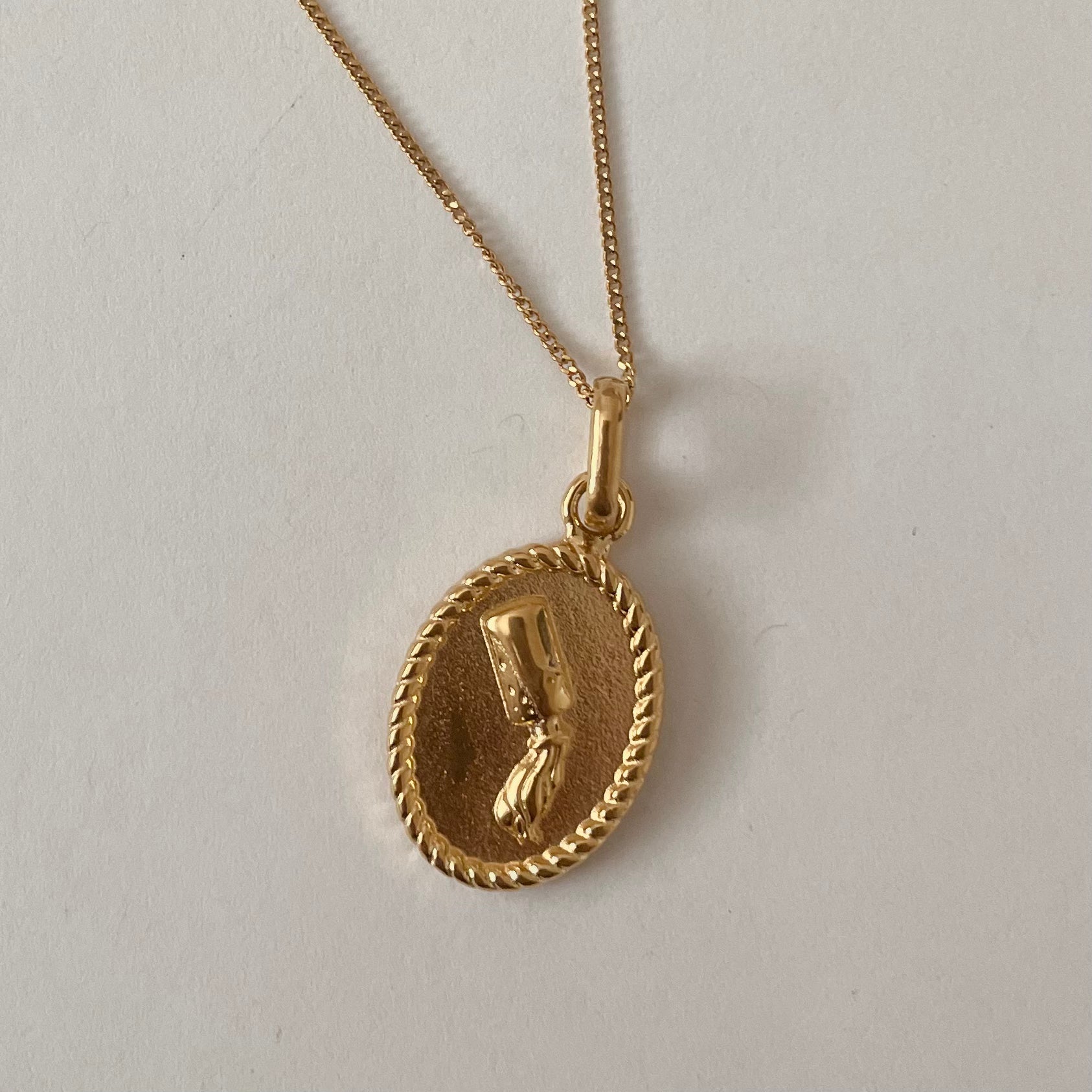 The Zodiac 2.0 Necklace - Gold features four gold-plated pendants with intricate designs, displayed vertically on a simple background, making it an ideal choice for an astrological necklace or hypoallergenic jewelry option.