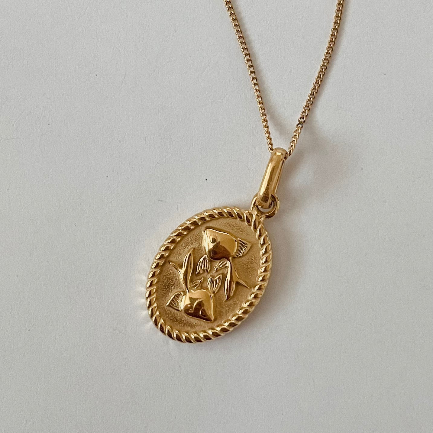 The Zodiac 2.0 Necklace - Gold features four gold-plated pendants with intricate designs, displayed vertically on a simple background, making it an ideal choice for an astrological necklace or hypoallergenic jewelry option.