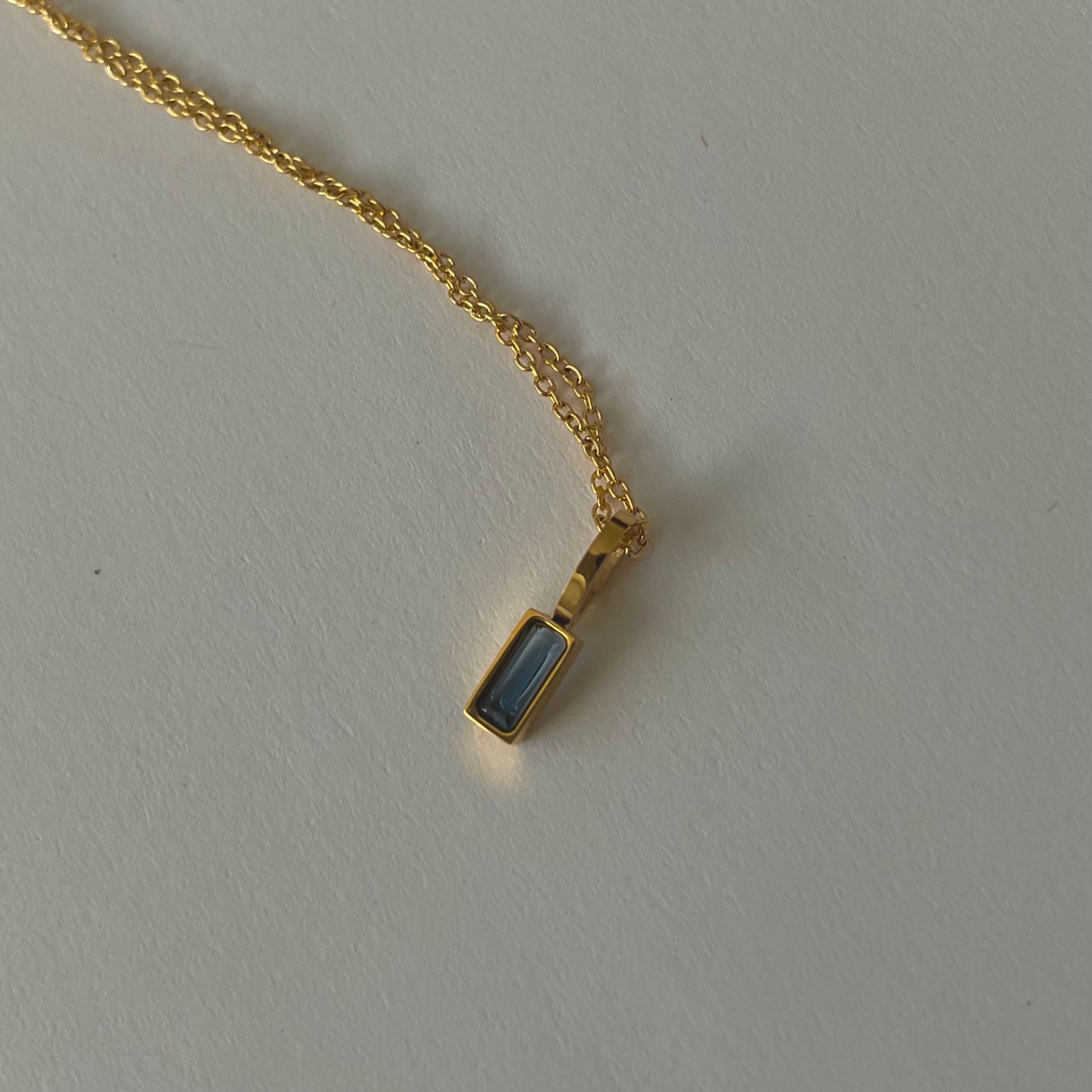 Birthstone necklaces, each featuring a rectangular gemstone pendant and thoughtfully handcrafted in Canada, are arranged neatly on a light surface.