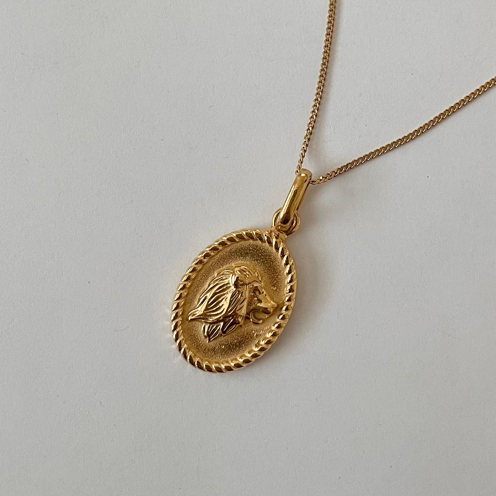 The Zodiac 2.0 Necklace - Gold features four gold-plated pendants with intricate designs, displayed vertically on a simple background, making it an ideal choice for an astrological necklace or hypoallergenic jewelry option.