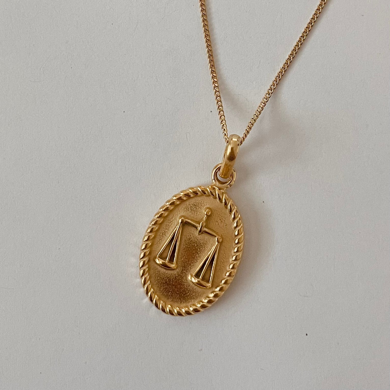 The Zodiac 2.0 Necklace - Gold features four gold-plated pendants with intricate designs, displayed vertically on a simple background, making it an ideal choice for an astrological necklace or hypoallergenic jewelry option.