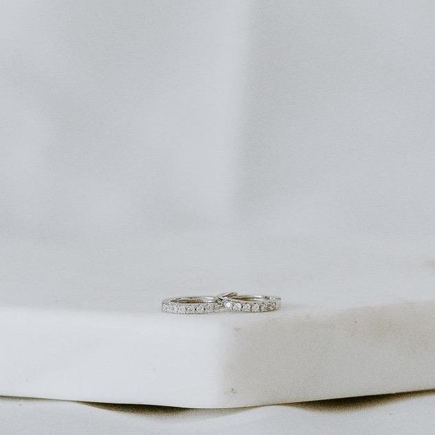 Four exquisite rings, named "Pave Huggies," crafted from 14k yellow and white gold and adorned with pave diamonds, are elegantly displayed on a white surface.