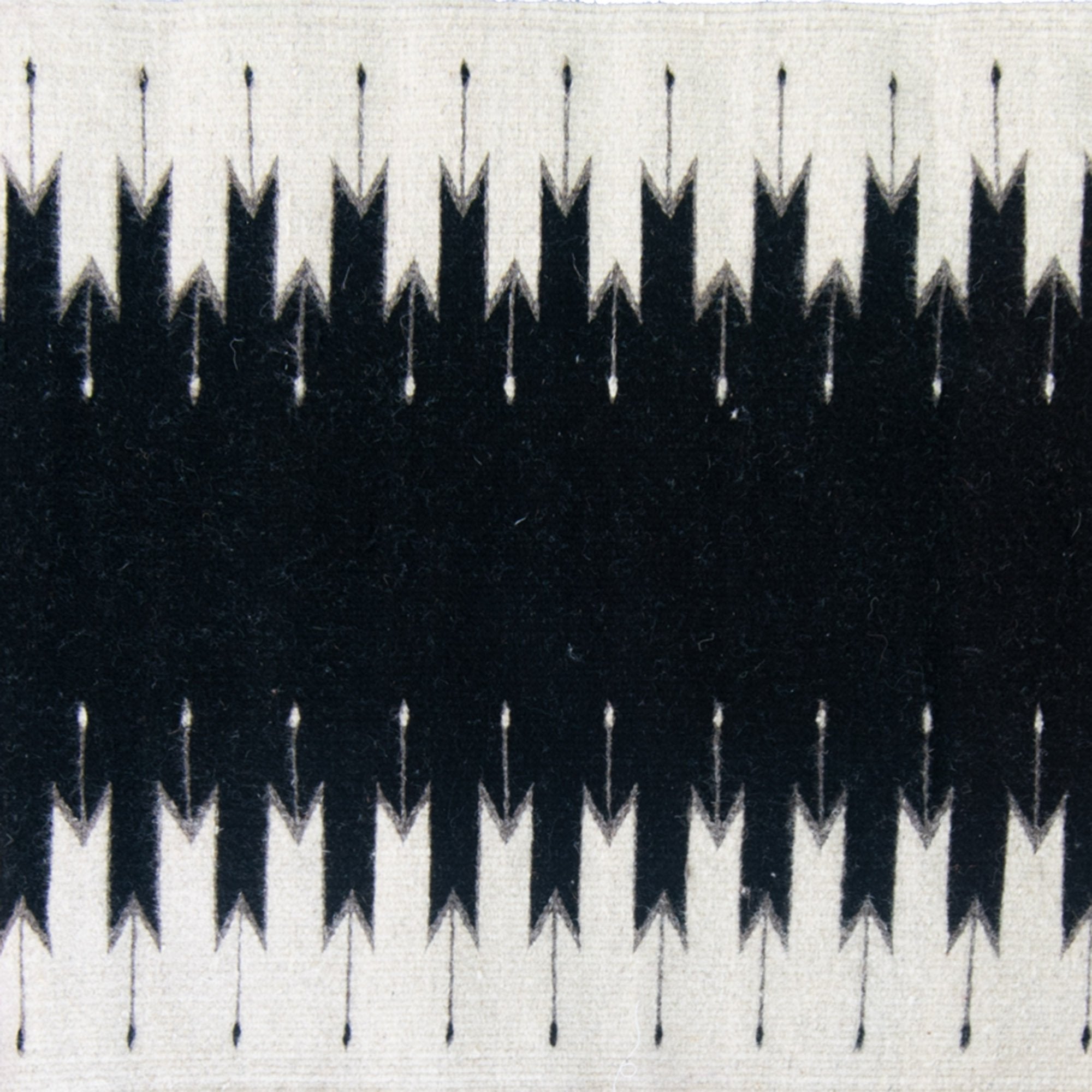 A mid-century modern leather armchair beside a white brick fireplace, with a Beleroó Handmade Southwestern Style Rug. Lightling Pattern in front and a metal watering can on the side.