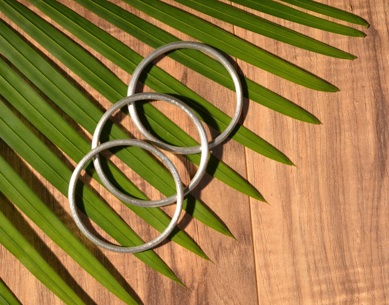 The Recycled Bombshell Bangle, crafted with recycled aluminum, features a smooth surface and is showcased against a plain white background.