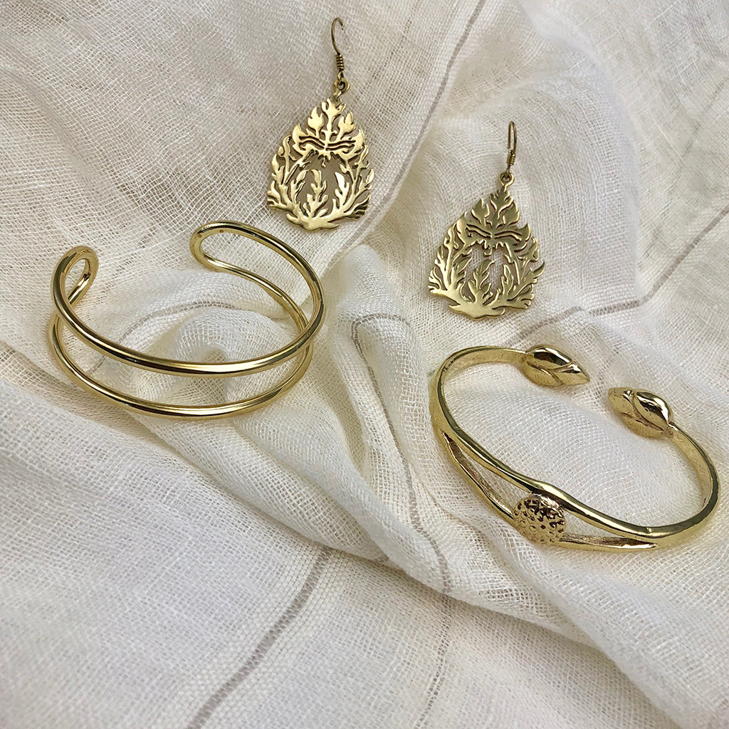 The Bombshell Wire Cuff is a gold double band cuff bracelet with an open-ended design, meticulously handmade in Cambodia. Crafted from recycled brass jewelry materials, this adjustable cuff combines both style and sustainability.