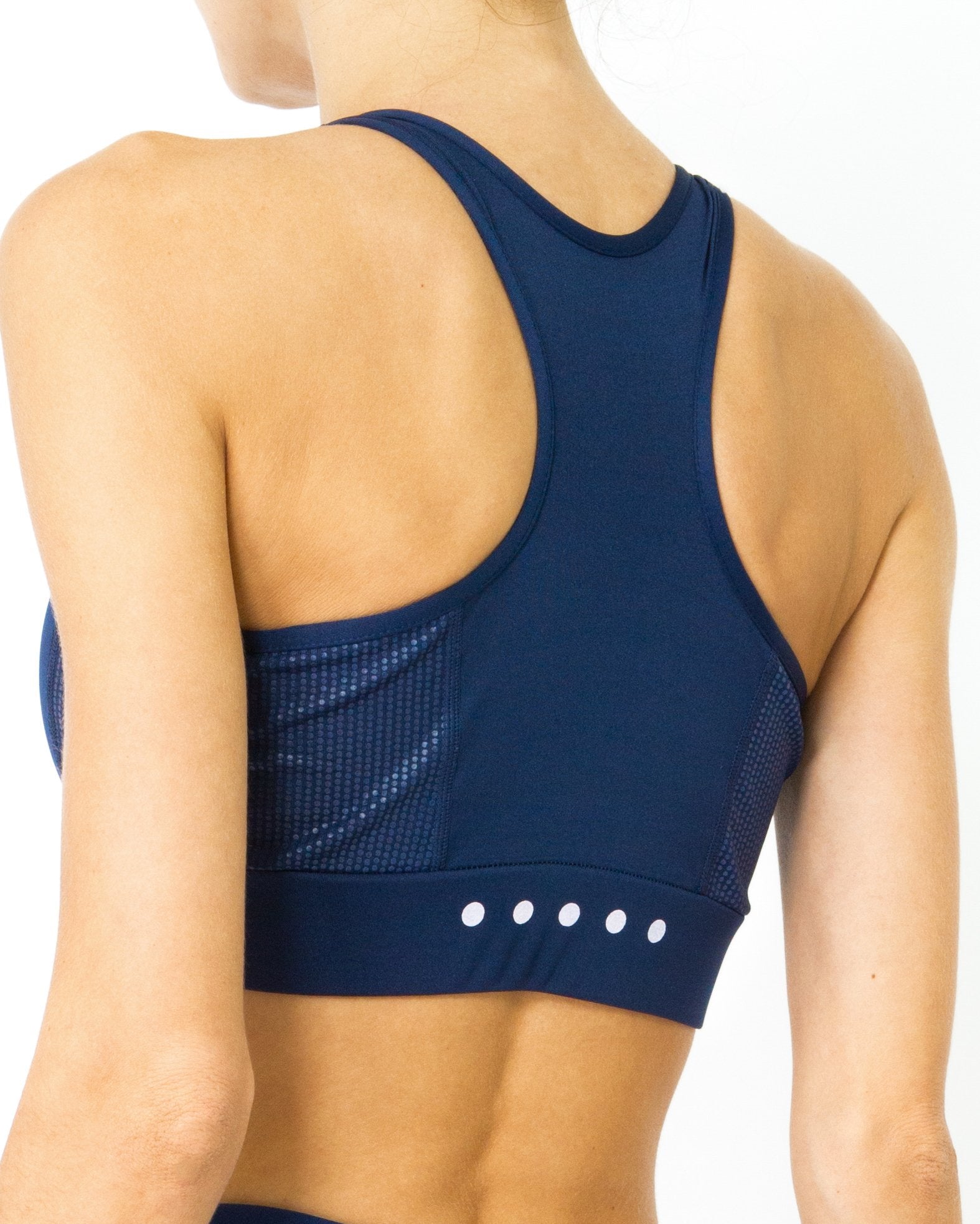 Someone wearing the Ashton Sports Bra in navy blue, featuring a racerback design.