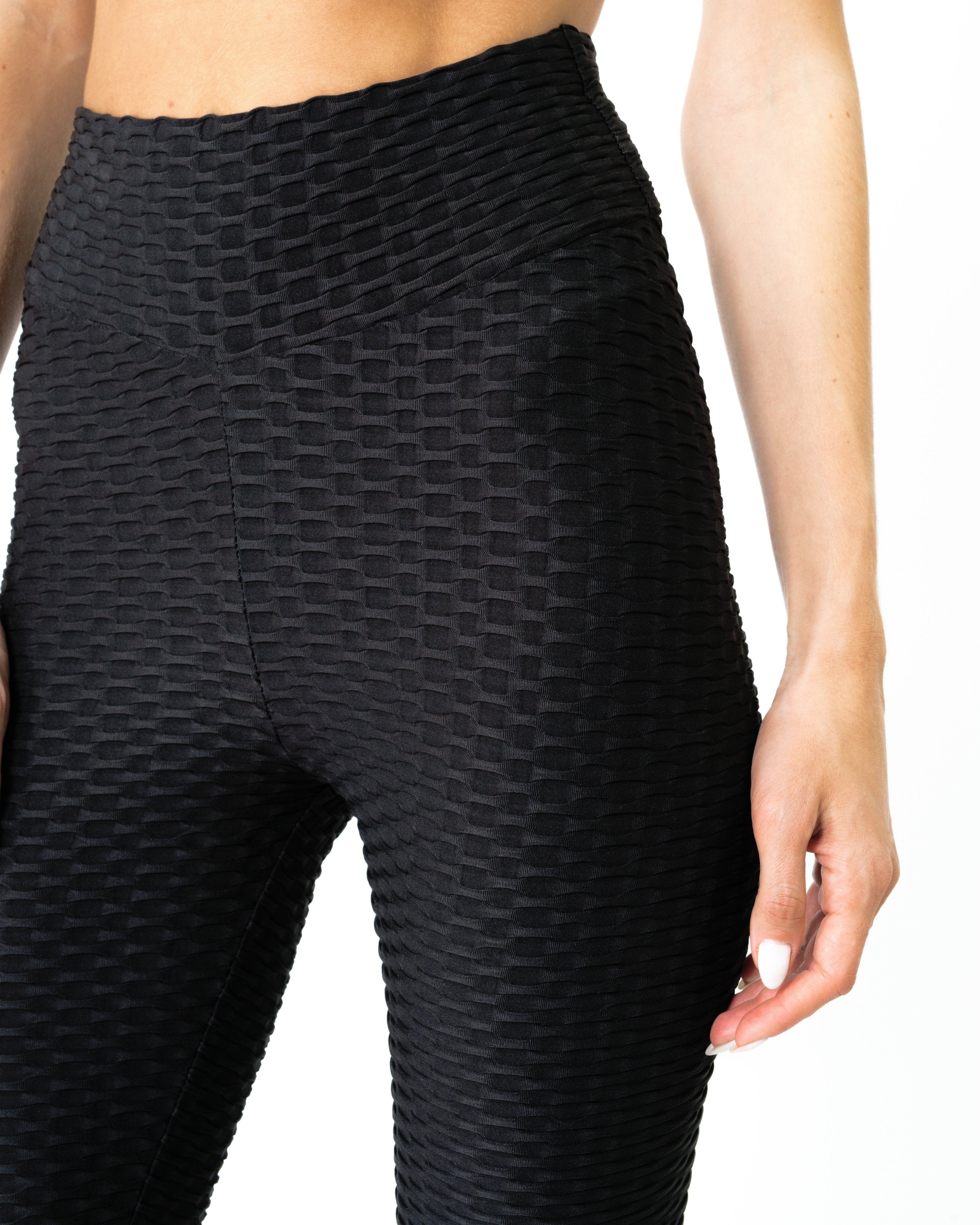 Against a crisp white background, someone effortlessly pairs high-waisted Bentley Leggings - Black, celebrated for tummy control and butt-lifting features, with white sneakers.