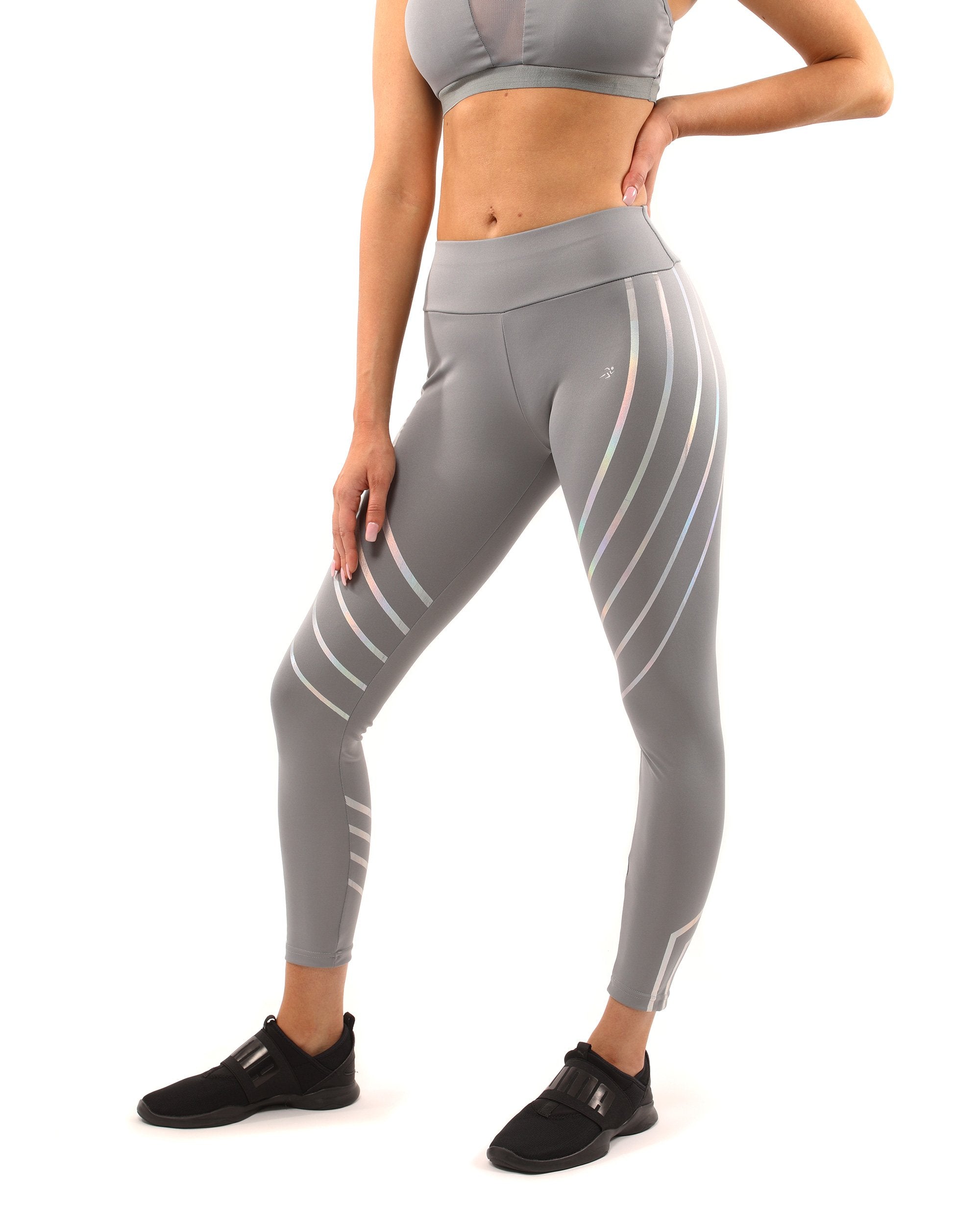 A person stands on a plain white background wearing the Laguna Set - Leggings & Sports Bra in grey, featuring geometric patterns.