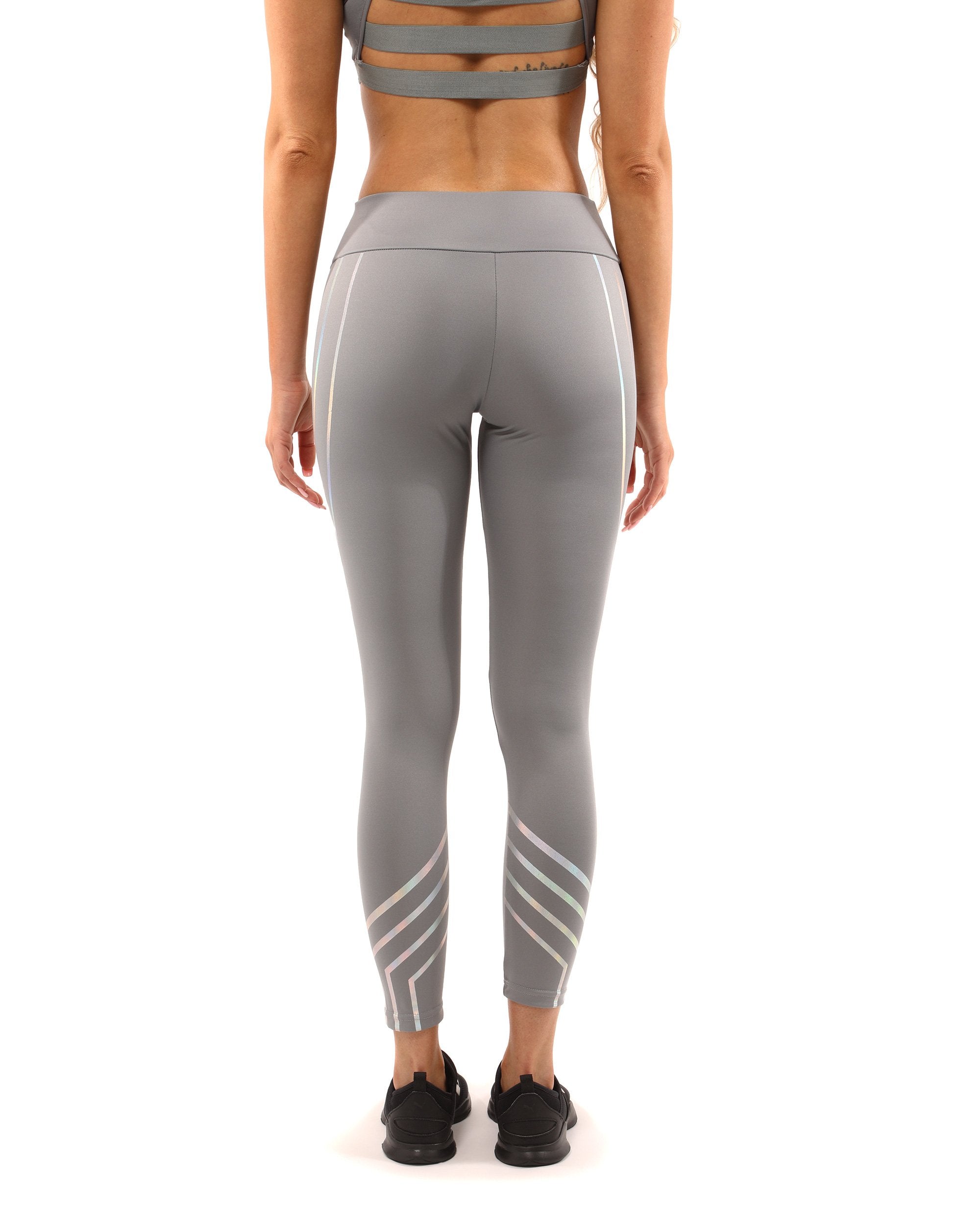 A person stands on a plain white background wearing the Laguna Set - Leggings & Sports Bra in grey, featuring geometric patterns.