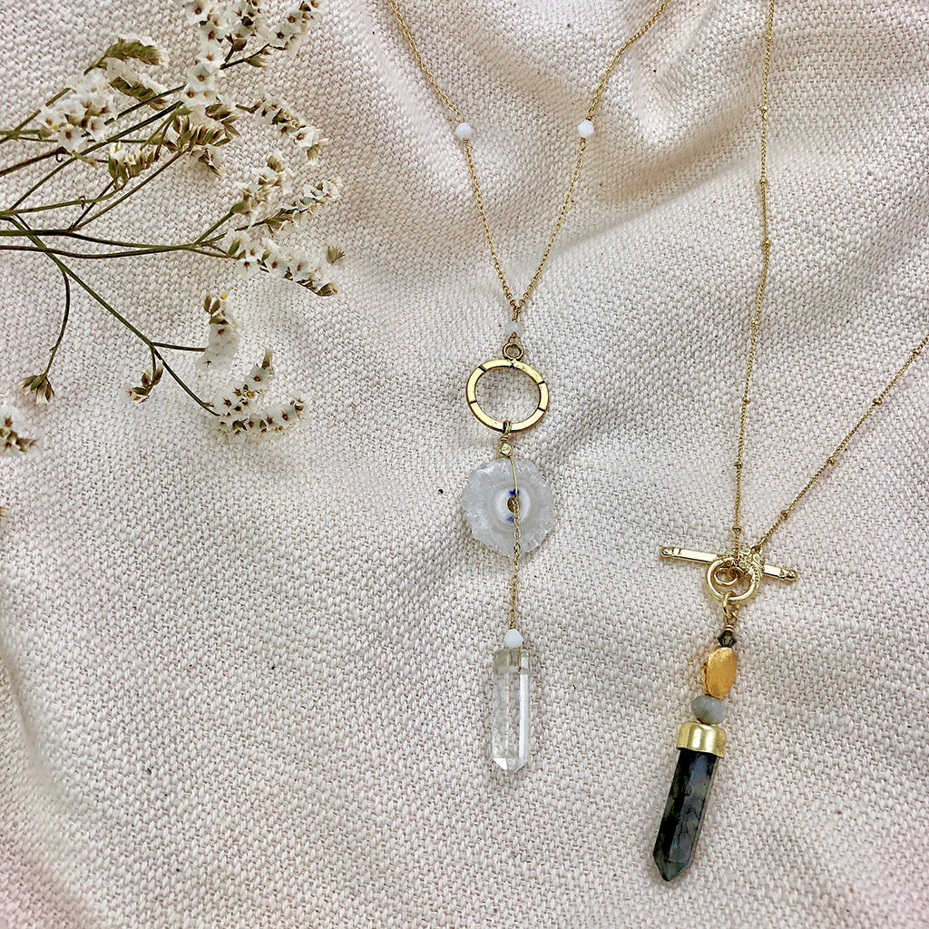 The Solar Quartz + Crystal Y Necklace is an enchanting piece of handmade jewelry, featuring a gold necklace with a circular pendant and two stunning stones, including solar quartz.