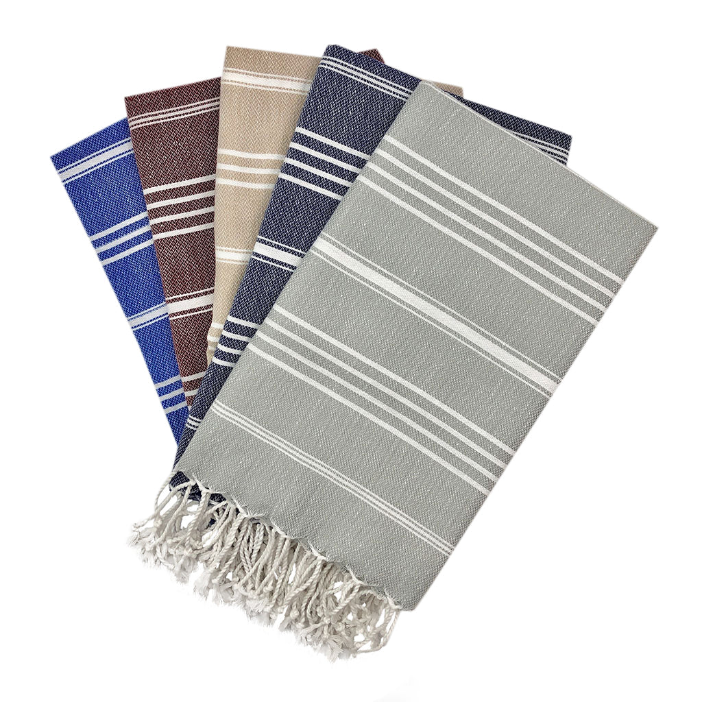 The Classic Turkish Hand Towels in five elegant striped designs, featuring shades of blue, brown, beige, navy, and grey, are beautifully displayed. Made from 100% Turkish cotton and adorned with white fringe on one end, they offer exceptional absorbency for all your needs.