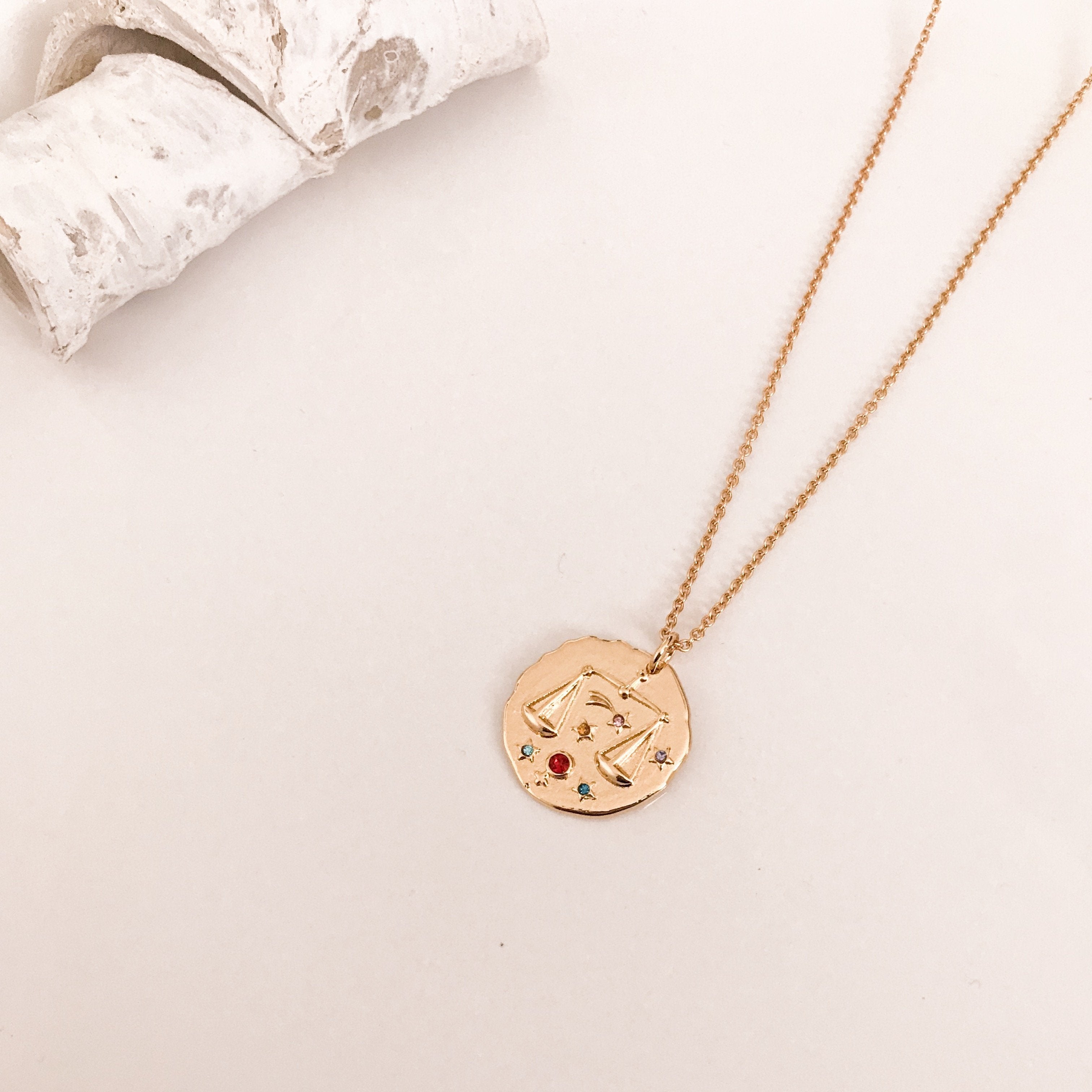 Discover our Wanderlust Zodiac Necklace collection, featuring exquisite hanging gold pendants with intricate designs on delicate chains. Some necklaces are embellished with vibrant gemstones. Crafted with hypoallergenic 18K gold plating, these pieces effortlessly combine elegance and comfort for everyday wear.