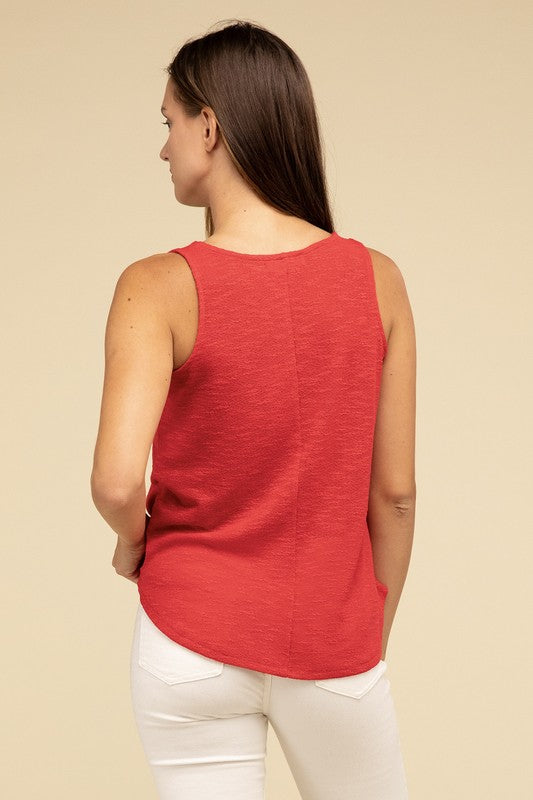 A woman in a stylish and adaptable V Neck Sleeveless Cami Top paired with jeans stands against a beige background. She has long brown hair and maintains a neutral expression.