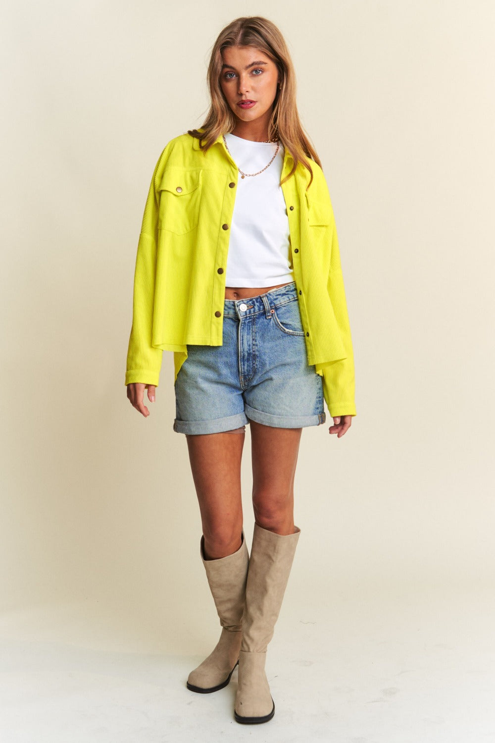 Person wearing a relaxed fit, bright yellow J.NNA Snap Down Long Sleeve High Low Shacket over a white top and denim jeans, smiling against a neutral background.