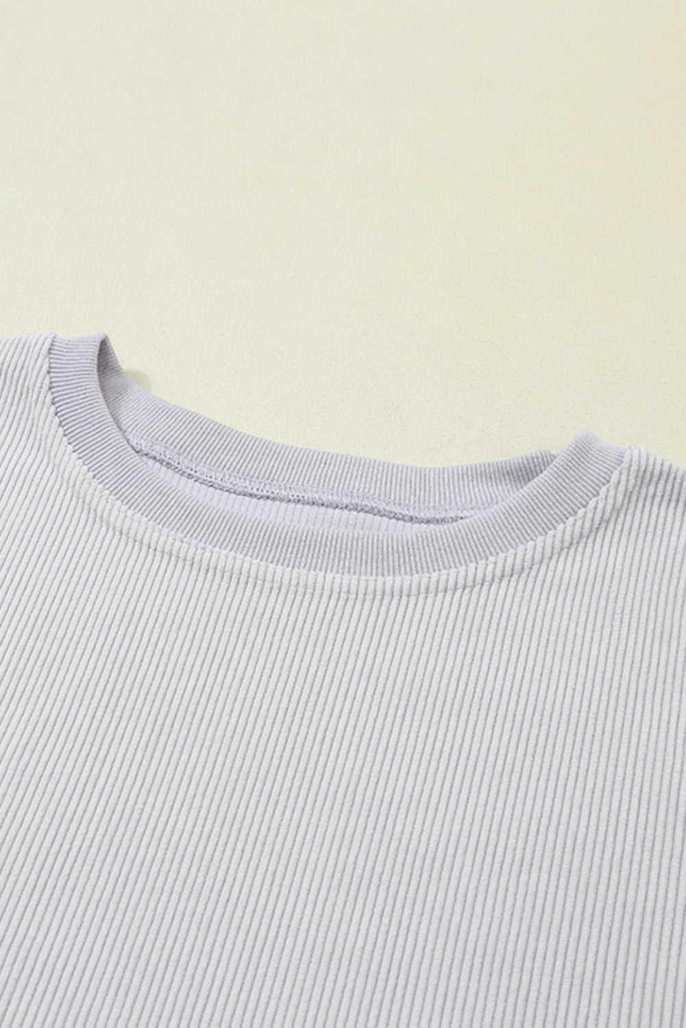 A woman wearing the Light Grey Ribbed Corduroy Oversized Sweatshirt with loose long sleeves, designed in corded fabric, making it fashionable for all body shapes.